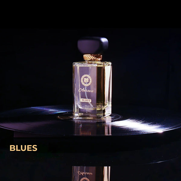Perfume bottle labeled 'Blues' on a dark surface with a black background